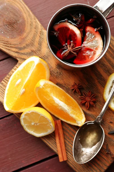 Mulled wine in a mug with citruses on wooden background, close up — Stock Photo, Image