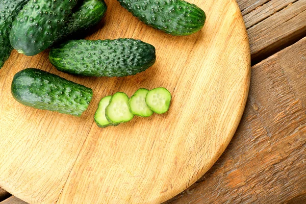 Gesneden komkommers op houten achtergrond — Stockfoto