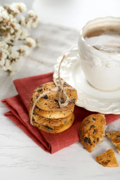 Tasse Kaffee und Haufen leckerer Kekse mit Schokoladenbröseln auf weißem Holztisch — Stockfoto