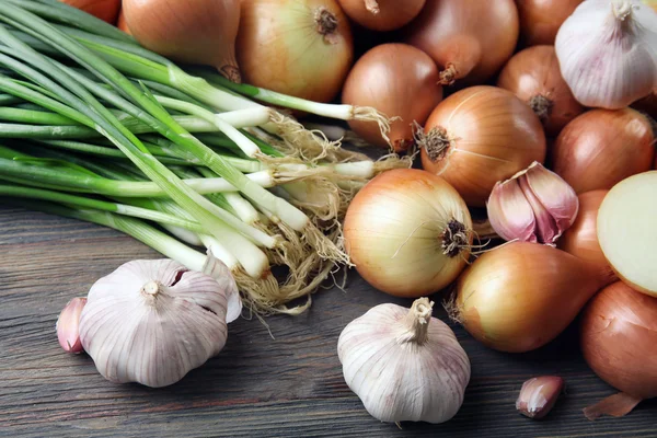 Verse verschillende uien met knoflook op houten achtergrond — Stockfoto