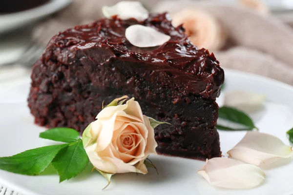 Pedazo de pastel de chocolate decorado con flores en la mesa de madera blanca — Foto de Stock