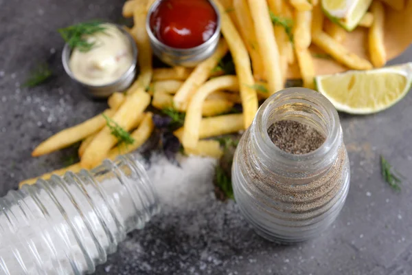 Franse frietjes in zak met saus, limoen en kruid op tafel — Stockfoto