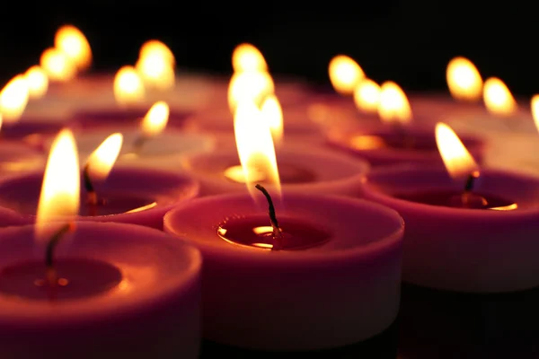 Molte piccole candele accese su sfondo scuro, primo piano — Foto Stock