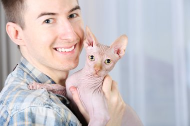 Açık renkli bir kedi tutan genç yakışıklı adam