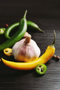 Koyu ahşap zemin üzerine sarımsak, yeşil ve sarı biber