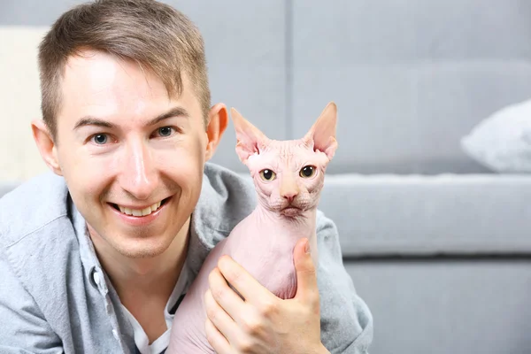 Junger schöner Mann liegt mit Katze zu Hause auf dem Boden — Stockfoto