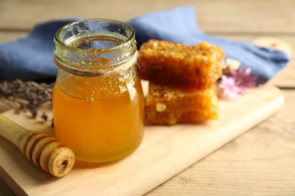 Glazen pot met honing, honingraten en noten op houten achtergrond — Stockfoto