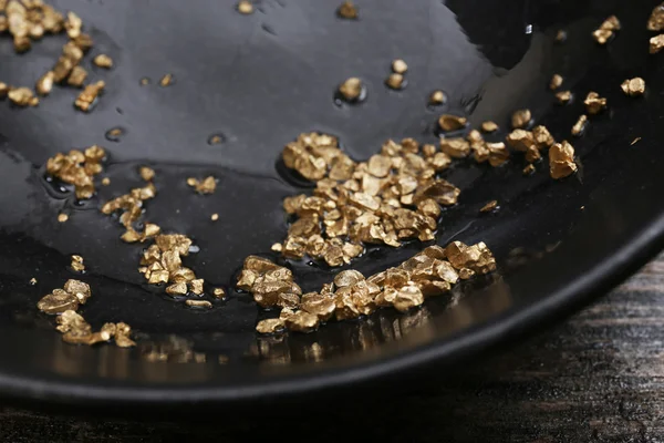 Gouden Goudklompje korrels, op zwarte plaat, close-up — Stockfoto