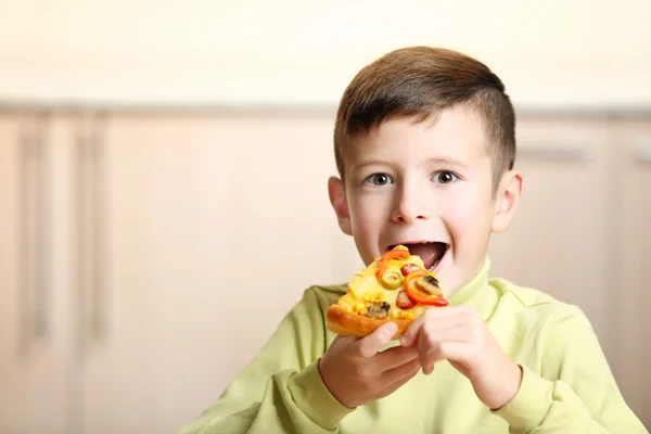 Malý chlapec jíst pizzu doma — Stock fotografie