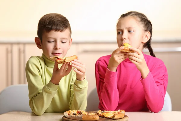 Děti jíst pizzu doma — Stock fotografie