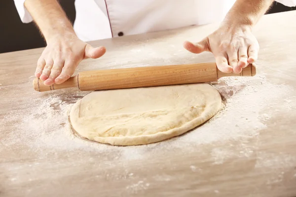 Ręce toczenia ciasta na pizzę na drewnianym stole, zbliżenie — Zdjęcie stockowe