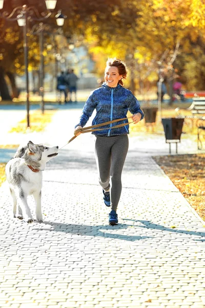 Mulher correndo com seu cão no parque — Fotografia de Stock