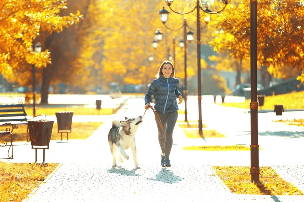 女人和她的狗在公园里慢跑 — 图库照片