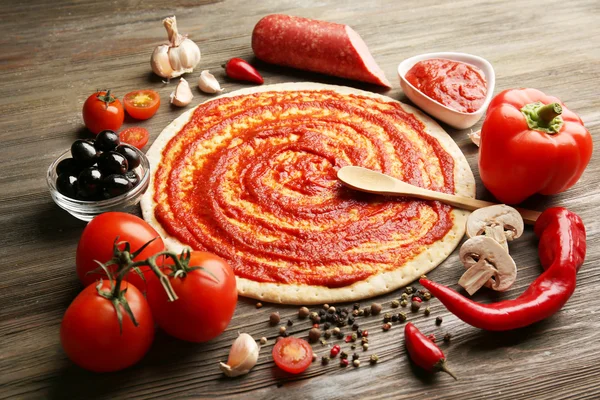 Tészta alapot a ketchup és összetevők a pizza, az asztalon — Stock Fotó