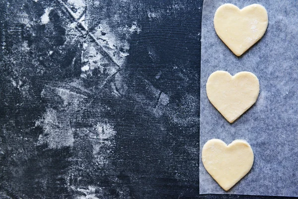 Uncooked heart shaped biscuits on a baking paper — Stock Photo, Image