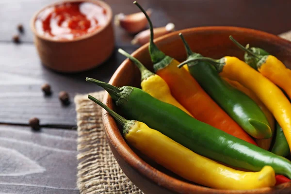 Peperoni, salsa piccante fatta in casa e spezie su sacco, su sfondo di legno — Foto Stock