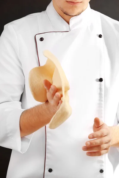 Mann bereitet Teigbasis für Pizza auf dem Holztisch vor, Nahaufnahme Stockfoto