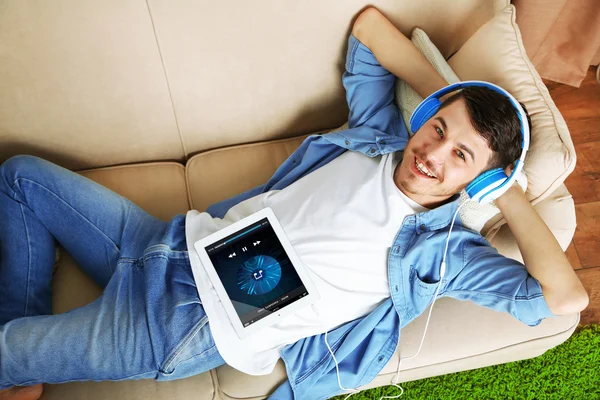 Hombre en el sofá escuchando música — Foto de Stock