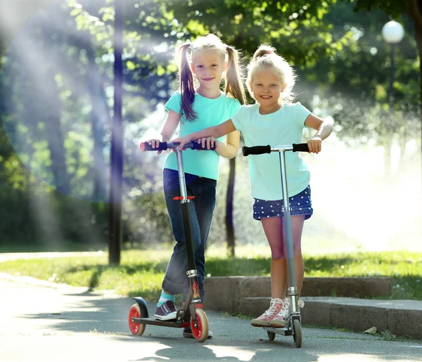 Small girls riding on scooters — Stock Photo, Image