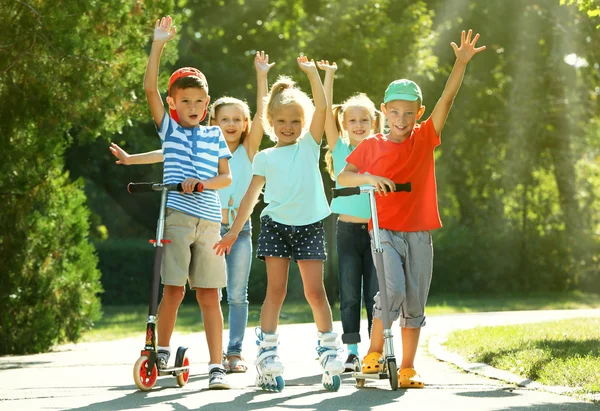 Crianças andando em scooters e patins — Fotografia de Stock