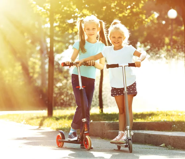 Kleine meisjes rijden op scooters — Stockfoto