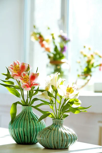 Mooie Alstroemeria bloemen in Aquamarijn vazen op achtergrond van venster — Stockfoto