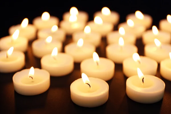 Brennende Kerzen in einer Reihe auf schwarzem Hintergrund — Stockfoto