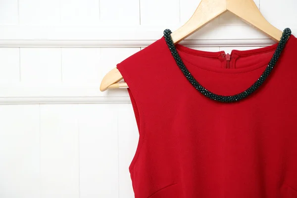 Blusa y collar en percha sobre fondo de pared — Foto de Stock