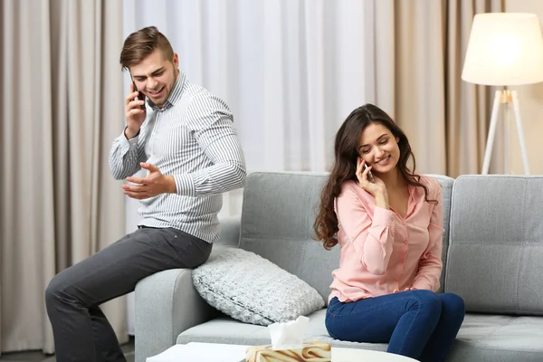 Pareja con teléfonos móviles en casa — Foto de Stock