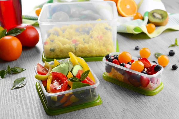 Smakelijke lunch in plastic containers op houten tafel close-up — Stockfoto