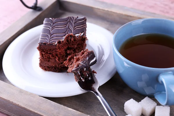 Served table with a cup of tea and chocolate cake on wooden background close-up — Stock Photo, Image