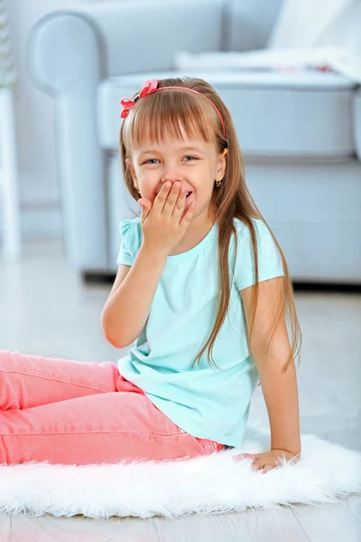 Pequena menina bonito sentado no tapete — Fotografia de Stock