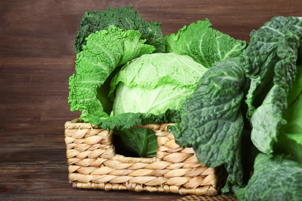 Savoy cabbage in wicker basket on wooden background — Stock Photo, Image