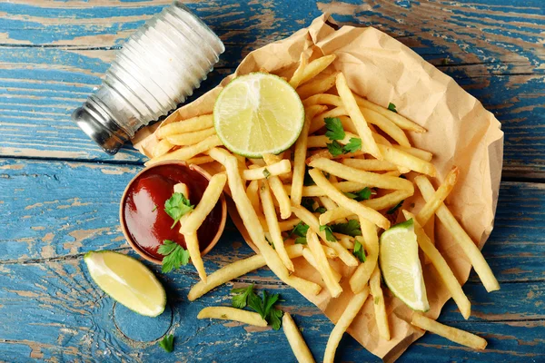 French fried potatoes on craft paper on cutting board — Stock Photo, Image