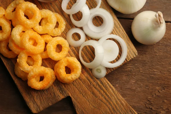 Anéis de batatas fritas com molho e cebola na tábua de corte — Fotografia de Stock