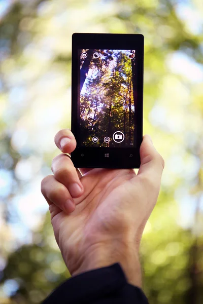 Telefon in der Hand auf dem Hintergrund der Natur — Stockfoto