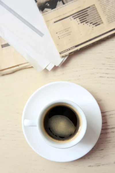 Cup of tasty coffee with newspaper on table