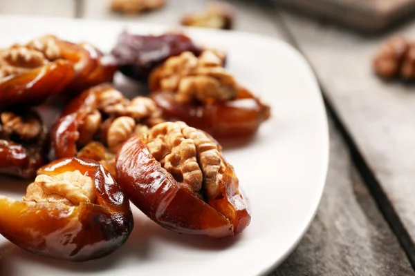 Walnut and date fruit in plate on wooden table, close-up — Stock Photo, Image