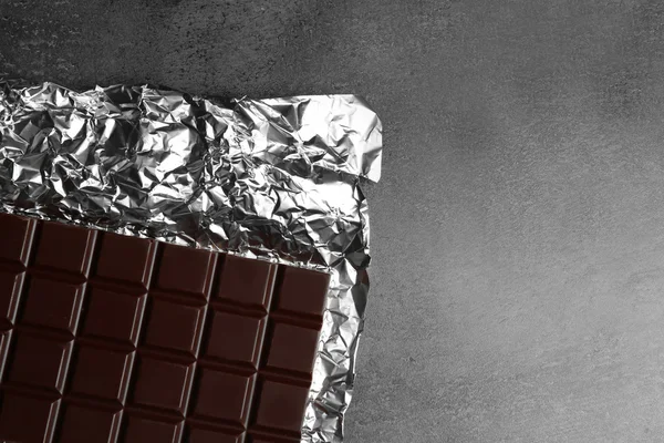 Chocolate bar in foil  on gray background — Stock Photo, Image