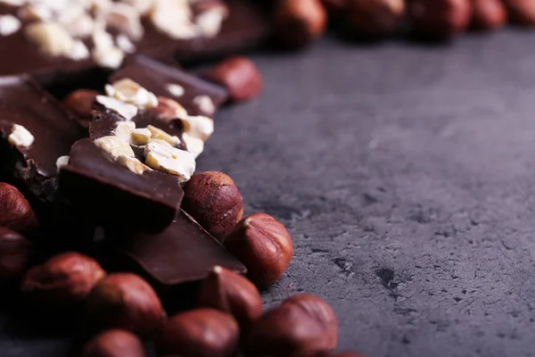 Pedaços de chocolate preto e nozes no fundo cinza escuro — Fotografia de Stock