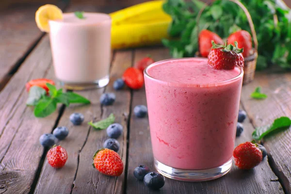 Vasos de batido frío fresco con frutas y bayas, sobre fondo de madera —  Fotos de Stock