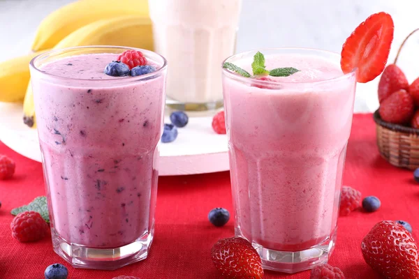 Milkshakes with berries at red textile on light background — Stock Photo, Image