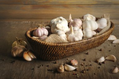 Ahşap arka plan üzerinde hasır kapta sarımsak