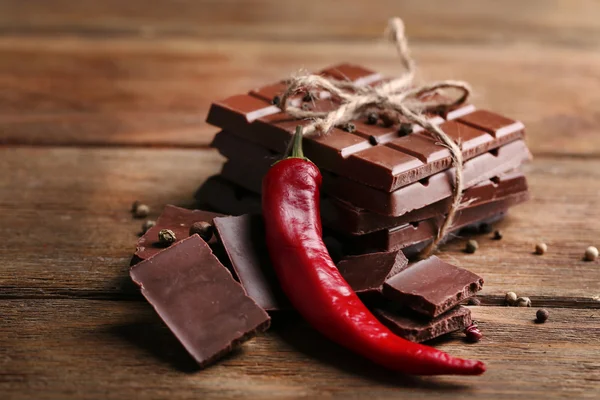Zwarte chocolade stukken met peper op houten achtergrond — Stockfoto