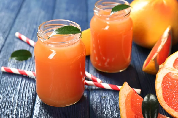 Succo di pompelmo in bottiglia e frutta fresca su fondo di legno blu scuro — Foto Stock