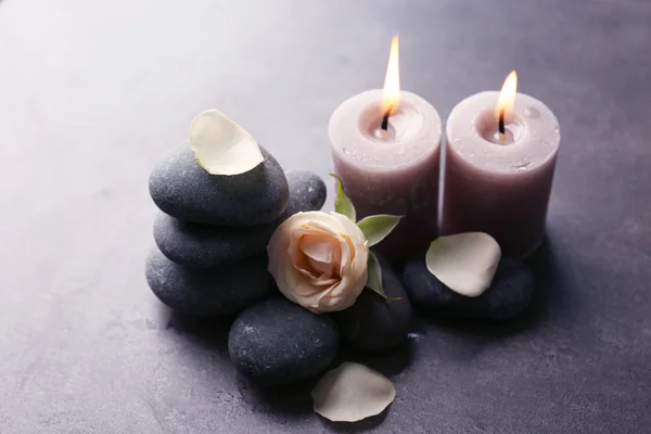Концепция отдыха - композиция ароматных свечей с галькой и цветком на сером фоне — стоковое фото