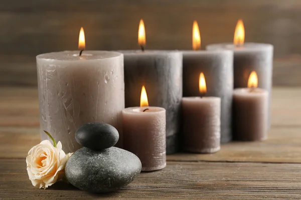 Candele grigio cera chiaro con rose su sfondo di legno — Foto Stock