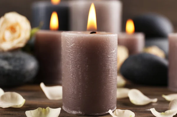 Красивая расслабляющая композиция зажженных свечей, гальки и цветов на деревянном фоне — стоковое фото