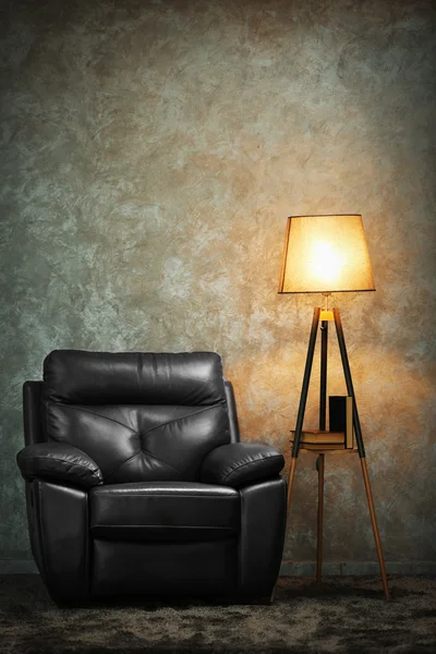 Silla de cuero negro y lámpara sobre fondo de pared gris — Foto de Stock