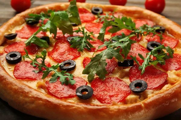 Smakelijke pizza salami versierd met tomaten op houten achtergrond, close-up — Stockfoto